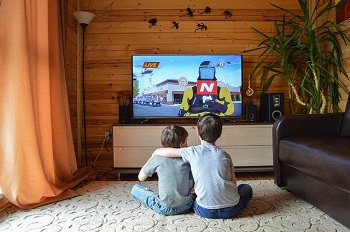 two little boys sit together watching TV, likely increasing screen time during the pandemic